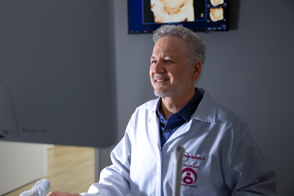 Dr. Orlando Monteiro Jr. sorrindo ao lado de um equipamento de exames de imagem